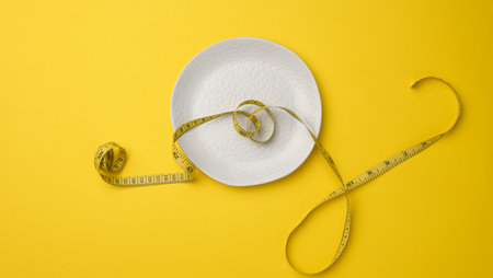 empty white ceramic plate and measuring tape on yellow background. Healthy nutrition concept, weight lossの写真素材