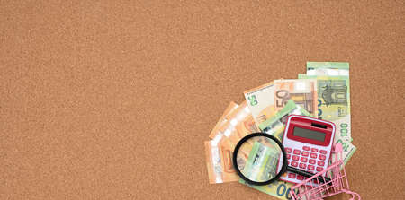 magnifier and paper euro bills on brown background. The concept of saving on purchases, increasing the price of goodsの写真素材