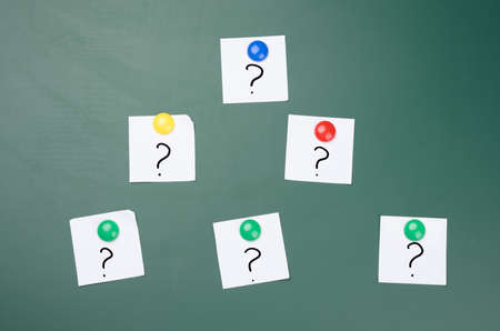 question marks are drawn on white pieces of paper, green chalk boardの写真素材