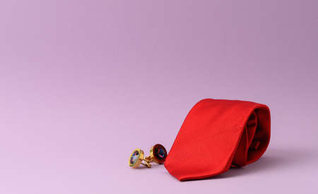 twisted silk red tie and cufflinks on a purple background, close up