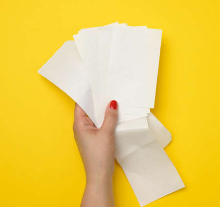 female hand holds a stack of paper checks on a yellow background. Account analysis, taxesの写真素材