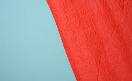 crumpled sheet of red paper on a blue background, creases and scuffs. Place for inscription, full...