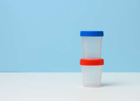 empty plastic container for the collection of analyzes on a white table, blue backgroundの写真素材