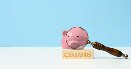 wooden magnifier and pink ceramic piggy bank, lettering crisis. Analysis of the securities market,...
