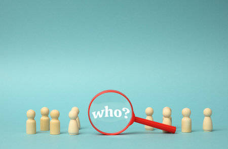 wooden figures of men stand on a blue background and a plastic magnifying glass. Recruitment concept, search for talented and capable employees, career growthの写真素材