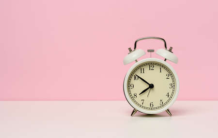 white metal alarm clock on a white table, ten to eight in the morning, copy space