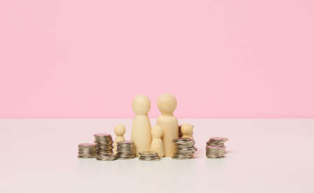 stack of metal coins and wooden figures of men on a white table. Savings and expenses, family budget, subsidies from the stateの写真素材