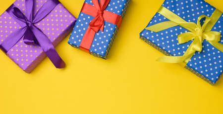 gift box tied with silk ribbon on a yellow background, top view. Festive backdrop, copy space