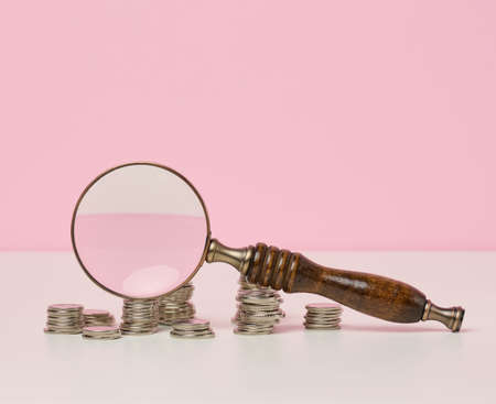 wooden magnifier and white coins on the table. Income growth concept, high percentage of investment....