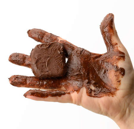 female hand holding a melted piece of dark chocolate, hand smeared with chocolate on a white backgroundの写真素材