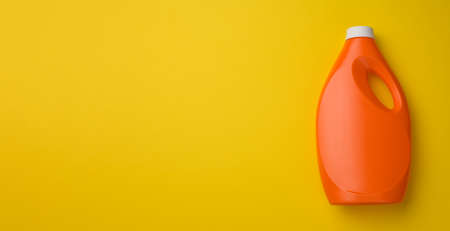 orange plastic bottle for liquid washing powder on yellow background, top view, copy spaceの写真素材