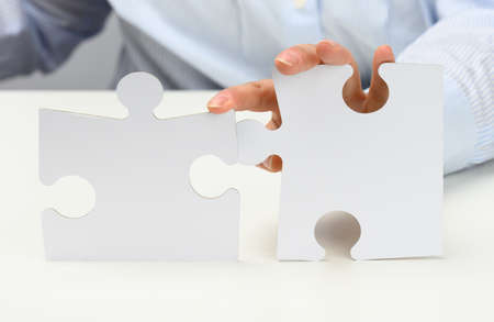 female hands hold white large paper puzzles. Solution concept, strategy and goal achievement, close...