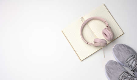 pink wireless headphones, a pair of gray sneakers and notepad on a white background, top view. Womens clothingの写真素材