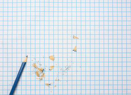 sharpened wooden pencil with shavings on a checkered paper sheet, copy spaceの写真素材