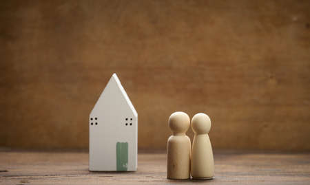 wooden family figurines, model house on a brown background. Real estate purchase, rental concept. Moving to new apartmentsの写真素材