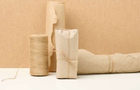 box, roll of brown kraft paper and reel with brown rope on white table, packing material, zero wasteの写真素材