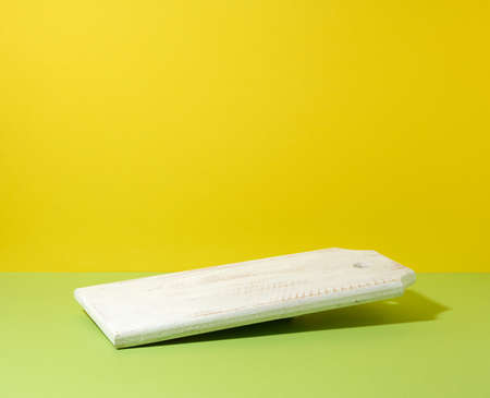 rectangular empty white wooden kitchen board on yellow green background, utensils