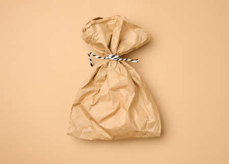 full brown paper disposable food bag on a beige background, concept of delivery and ordering, top view, zero wasteの写真素材