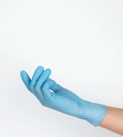 Doctor's hand in a blue medical glove holds an object on a white background. Copy space, hold any...