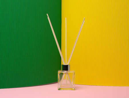 glass flask and wooden sticks, aroma lamp on colored backgroundの写真素材