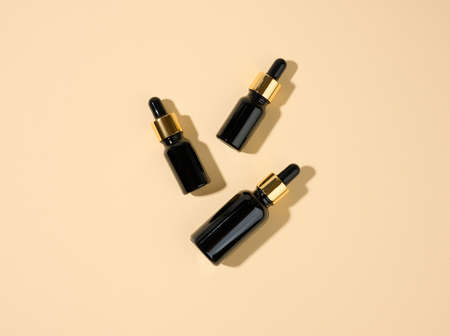 glass cosmetic brown bottles with a pipette on a beige background. Cosmetics SPA branding mockup,...
