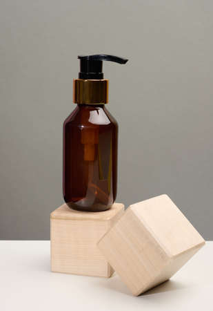 Brown glass bottle with black pump of cosmetic products on wooden block. Natural organic spa cosmetic, beauty concept. Mockupの写真素材