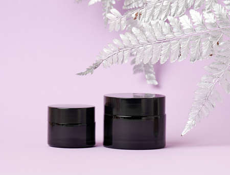 black glass jar for cosmetics on a purple background. Packaging for cream, gel, serum, advertising and product promotion, mock upの写真素材