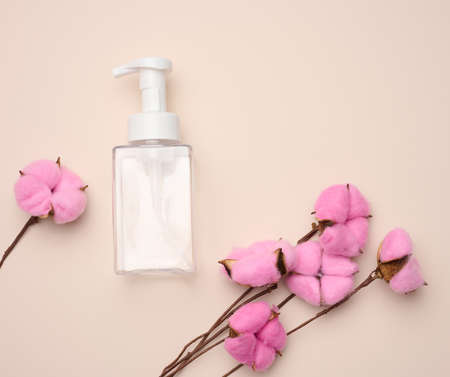 empty plastic container with dispenser for liquid products, soap or shampoo on beige backgroundの写真素材