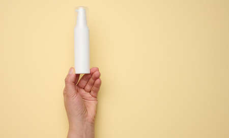 female hand holding white plastic bottle. Packaging for cream, gel, serum, advertising and product promotionの写真素材