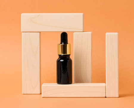 black glass bottle with a dropper for cosmetics on an orange background. Packaging for gel, serum, advertising and promotion. Natural organic products. Mock upの写真素材