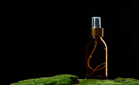 brown glass spray bottle stands on green moss. Cosmetics SPA branding. Packaging, advertising and product promotion, mock upの写真素材