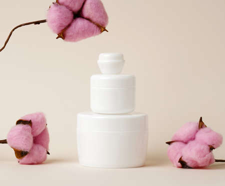 cosmetic products in a white plastic jar with lid. Blank for branding products, moisturizer on beige background, mock upの写真素材