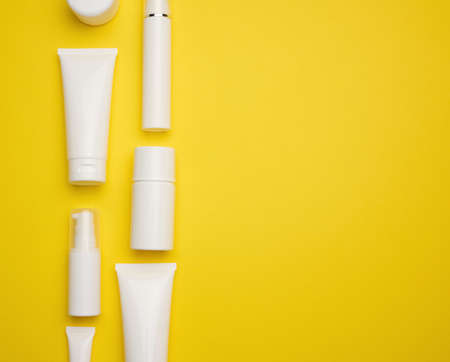 jar, bottle and empty white plastic tubes for cosmetics on a yellow background. Packaging for cream,...