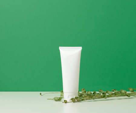 empty white plastic tubes for cosmetics on a green background. Packaging for cream, gel, serum, advertising and product promotion, mock upの写真素材