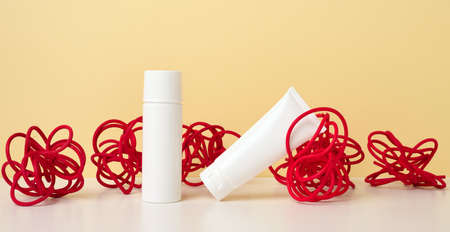 round container and empty white plastic tubes for cosmetics on a green background. Packaging for cream, gel, serum, advertising and product promotion, mock upの写真素材