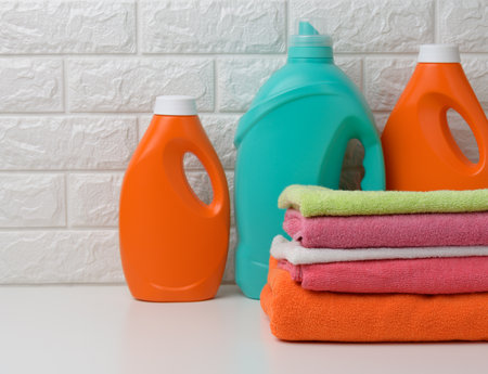plastic bottles with liquid detergent and folded towels on a white shelf. Bath interiorの写真素材