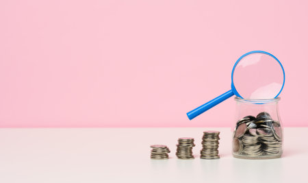 blue magnifier and white coins on the table. Income growth concept, high percentage of investment. Search for new sources of income, subsidyの写真素材