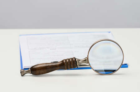 white paper sheets and a wooden magnifier on a white background, search for solutions and answersの写真素材