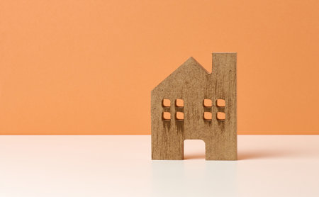 brown wooden house on a orange background. Real estate rental, purchase and sale concept. Realtor services, building repair and maintenance, copy spaceの写真素材