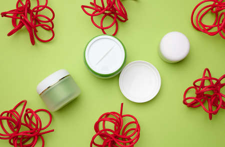empty white plastic jars for cosmetics on a green background. Packaging for cream, gel, serum, advertising and product promotion, mock upの写真素材