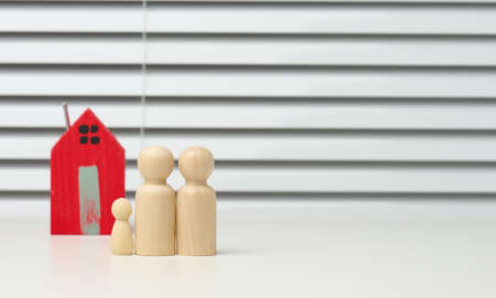 wooden family figurines, model house on a brown background. Real estate purchase, rental concept....