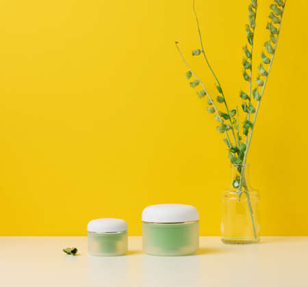 green jar for cosmetics on a white table. Packaging for cream, gel, serum, advertising and product promotion, mock upの写真素材