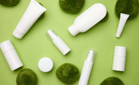 jar, bottle and empty white plastic tubes for cosmetics on a green background. Packaging for cream, gel, serum, advertising and product promotion, mock upの写真素材