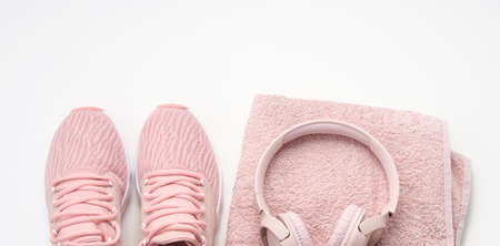 pair of pink textile sneakers, wireless headphones and a textile pink towel on a white background. Set for sports, runningの写真素材