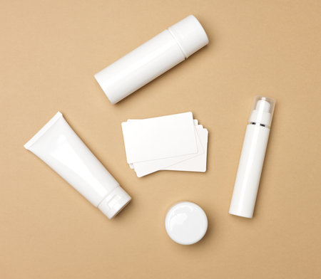 jar, bottle and empty white plastic tubes for cosmetics on a beige background. Packaging for cream, gel, serum, advertising and product promotion, mock up, top viewの写真素材