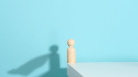 wooden figurine of a man and a shadow with a developing cloak, the concept of the strong and the winner. Everyone is stronger than he thinks, a superhero. Blue backgroundの写真素材