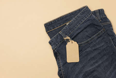 blank cardboard rectangular tag tied to blue jeans. Top view, copy space