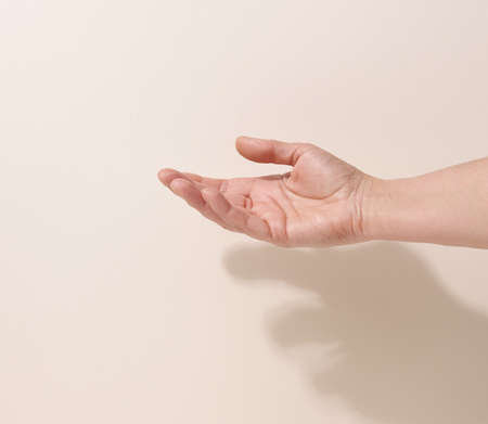female teen hand to hold something on a beige background. Advertising and product promotion
