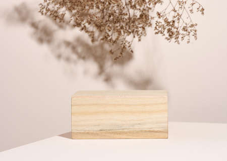 wooden podium to showcase cosmetics and other items, beige background with dry wildflowers and...