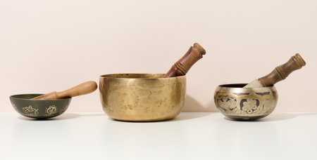 copper singing bowl and wooden clapper on a white table. Musical instrument for meditation,...